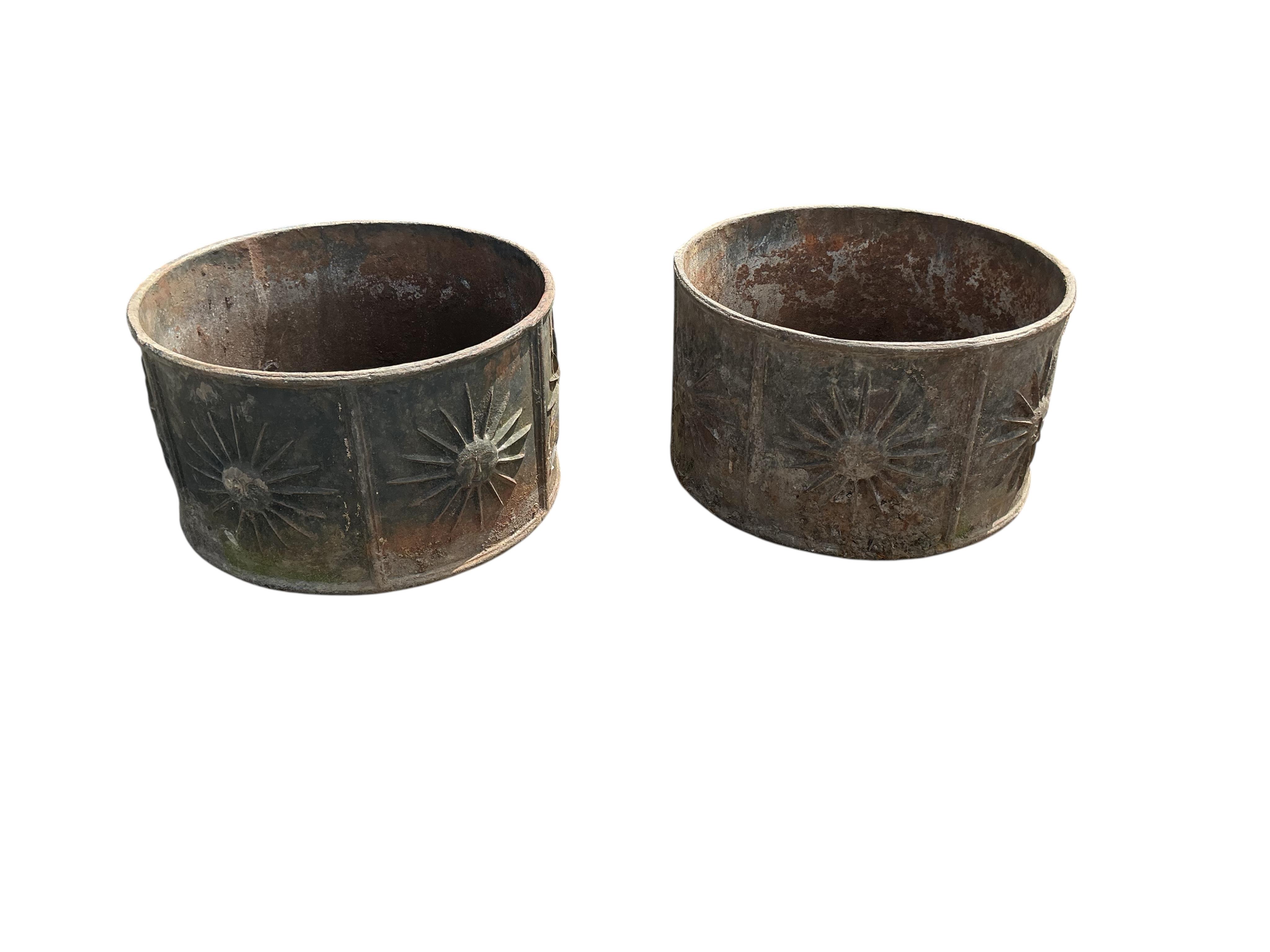 A pair of circular iron planters with cast relief sunburst panels, diameter 52cm, height 30cm